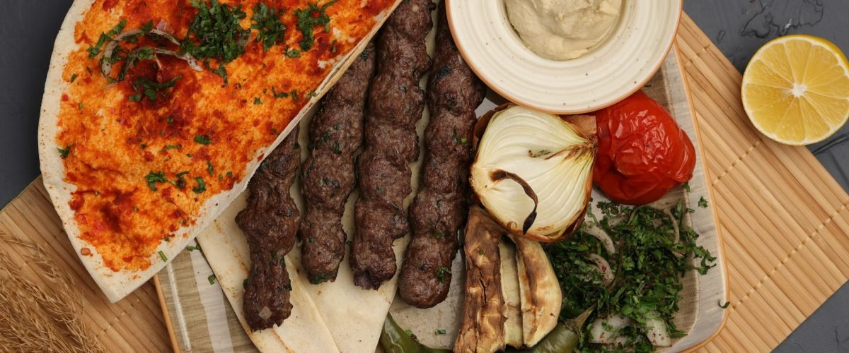 Grilled meat skewers with flatbread, grilled vegetables and dips